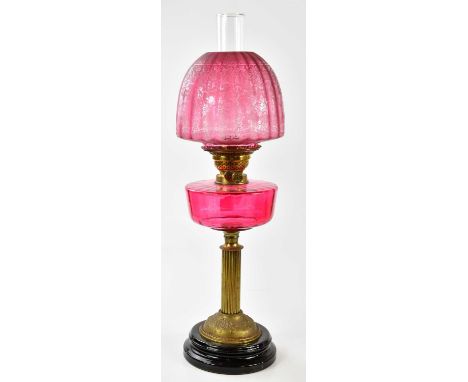 A late 19th century oil lamp, the dome shaped cranberry shade with etched floral decoration above the cranberry glass reservo