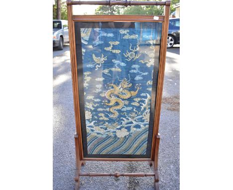 A 19th century Chinese silk embroidered panel depicting a four clawed dragon, now set in an Edwardian mahogany firescreen fra