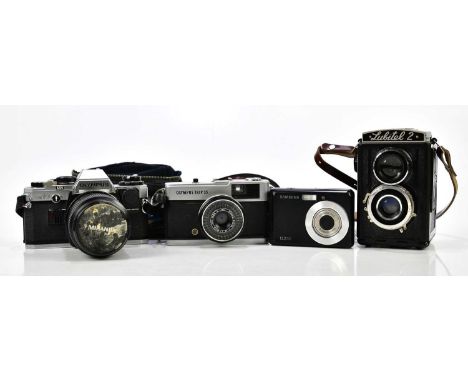 A group of four cameras, including Olympus OM10 with manual adapter and a 28270 lens, an Olympus Trip 35 in case, Samsung dig