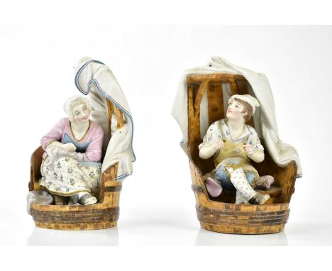 A pair of late 19th century Continental painted bisque figures representing a seated male and female, in a wood effect basket