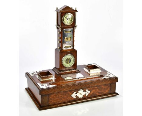 A late Victorian oak desk stand with silver plated mounts and with mounted detachable miniature long case clock set with Arab