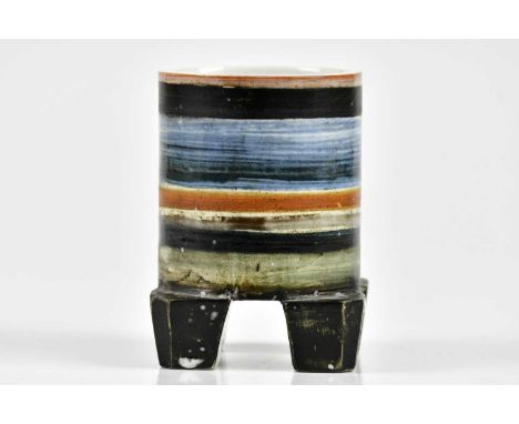 TROIKA POTTERY; a rare and unusual footed cylinder with linear decoration in colours of orange, brown, black and blue, emboss