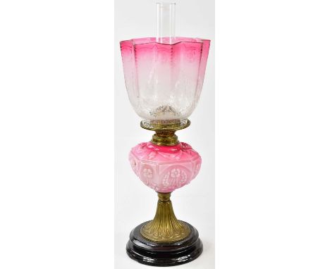 A late Victorian oil lamp, the cranberry and clear glass shade with etched decoration above the cranberry and milk glass moul