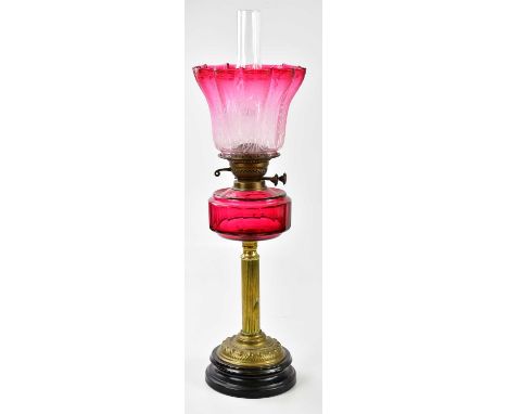 A Victorian oil lamp, the fluted cranberry and clear glass shade with etched floral decoration above the cranberry glass rese