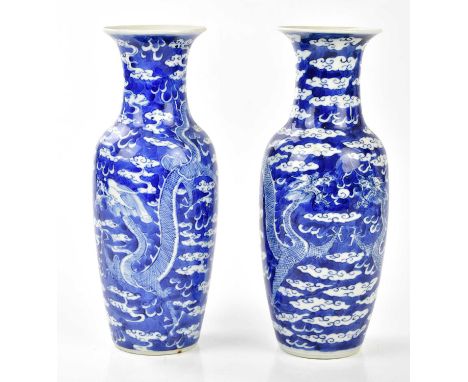 A pair of late 19th century Chinese blue and white porcelain vases with flared rims, decorated with four claw dragons chasing