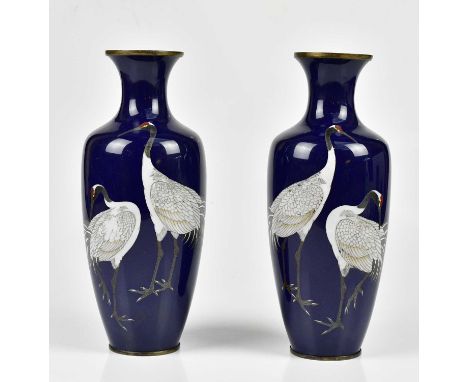 A pair of Japanese Meiji period cloisonne vases, each decorated with two cranes on a dark blue ground, unsigned, height 25cm.