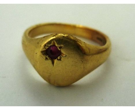 AN 18CT GOLD UNISEX SIGNET RING having oval un-engraved top set with a ruby 