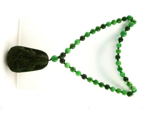 A SPINACH JADE PENDANT carved with a seated Buddha on a necklet, interspersed with emerald jadeite spherical beads, weight 17