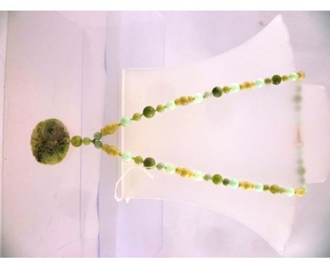 A NEPHRITE NECKLACE OF SPHERICAL BEADS, sampler colours, and carved pendant, 106g, 68cm long 