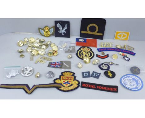 A collection of military uniform patches, cap badges and buttons