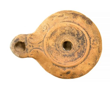 A Roman ceramic oil lamp in a buff orange fabric.C. 1st-4th century. 93mm x 68mm.