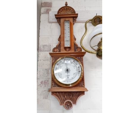 An Edwardian carved walnut barometer with thermometer