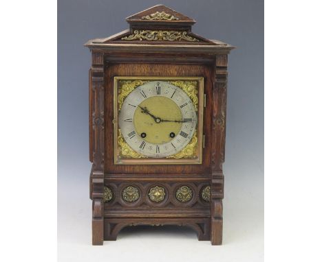 An oak cased mantel clock of architectural outline, with 16cm square brass dial and silvered Roman chapter ring, the movement