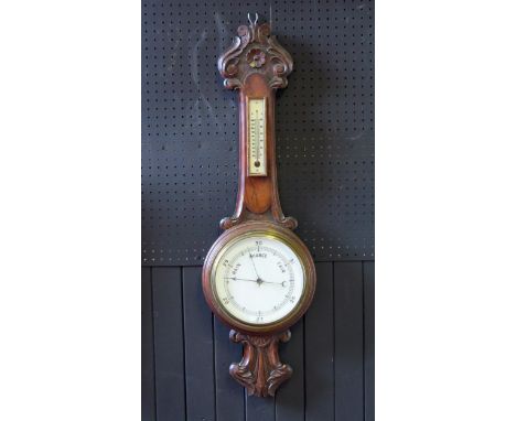 A late Victorian/Edwardian oak aneroid barometer  mounted on a onion topped case with foliate and scroll decoration, with alc