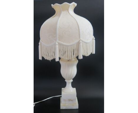 An Alabaster table lamp, of urn-shaped outline with writhen decoration, raised on a stepped a square base, with shade. 