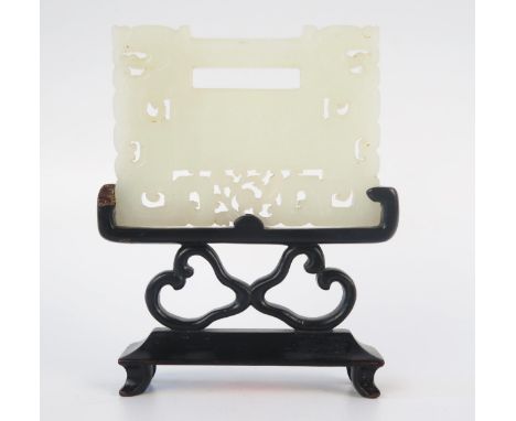 A Chinese carved jade panel, of rectangular pierced outline with four character marks to one side and a flower to the other, 