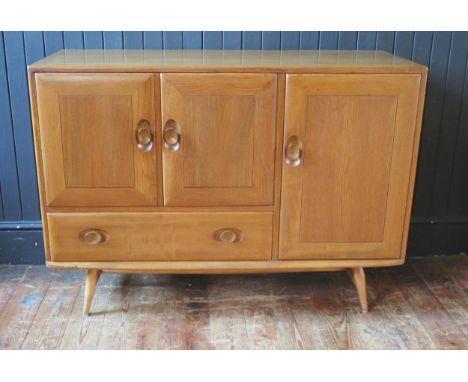 An Ercol sideboard of rectangular outline, containing an arrangement of a pair of cupboard doors a larger cupboard door and s