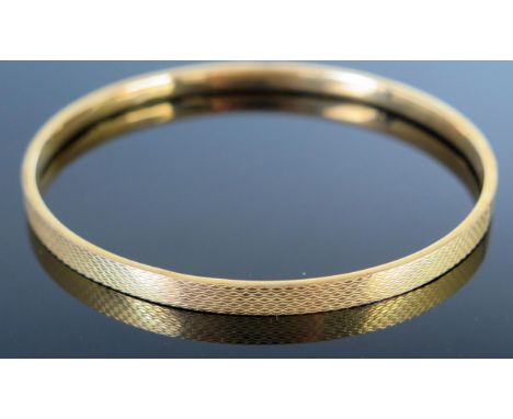 A 9ct Gold Bangle with engine turned decoration, 76mm internal diameter, 7.1g 