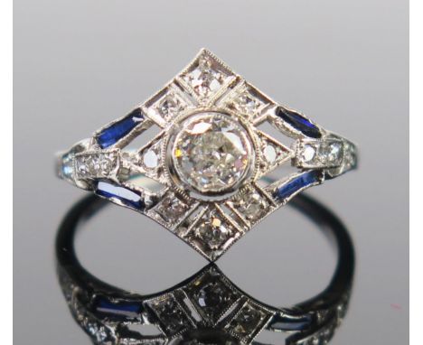 An Art Deco Sapphire and Diamond Ring in an unmarked precious white metal setting, the central c. 4.5mm brilliant round cut m
