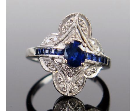 An Art Deco Style 18ct White Gold, Sapphire and Diamond Ring, the central oval cut claw set stone surrounded by millegrain se