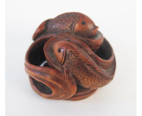 A boxwood netsuke carved as entwined carp, with inset with glass eyes, 4cm diameter. 