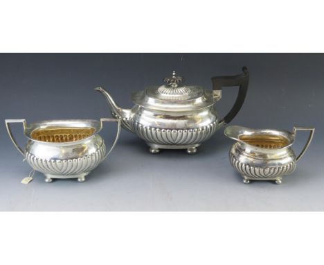 A matched silver three-piece tea service, maker Walker and Hall, Sheffield, 1896 and 1904, of barge-shaped outline, with half