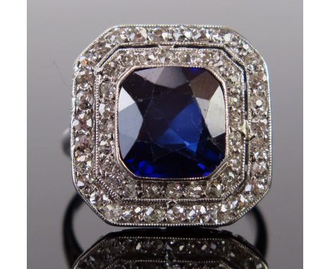 An Art Deco Sapphire and Diamond Ring in an unmarked white metal setting, the central c. 9.8x9.3mm, 7mm deep millegrain set s