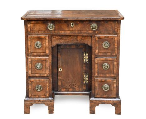 A George I Walnut, Crossbanded and Ebony-Strung Kneehole Desk, early 18th century, the quarter-veneered top with re-entrant c