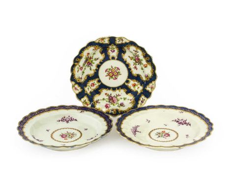 A Pair of Worcester Porcelain Plates, circa 1770, painted with a flowerspray within a gilt border on a ground of puce monochr