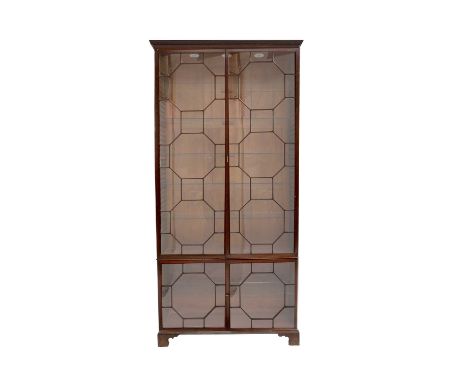 {} A George III Mahogany Bookcase, the dentil cornice above Chippendale-style astragal glazed doors enclosing later glass she
