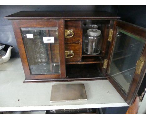 An early 20th Century oak cased smokers cabinet, with glass decanter and storage jar, also a hallmarked silver cigarette case