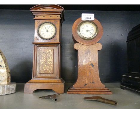An Arts & Crafts inlaid oak mantel clock, together with a further mantel clock in the form of a grandfather clock.