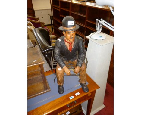 A modern model of Charlie Chaplin seated on a bench.
