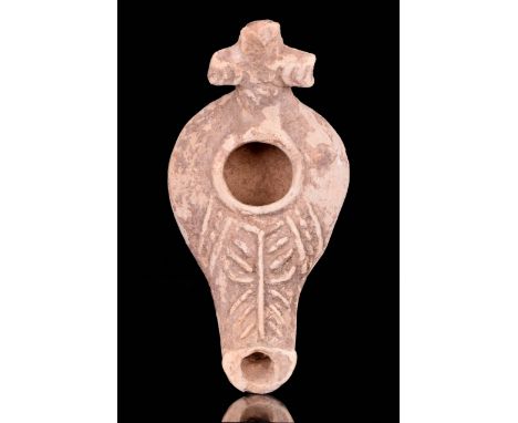 Ca. 5th-6th Century AD A large terracotta oil lamp featuring a cross-shaped handle, a circular discus with a large central fi
