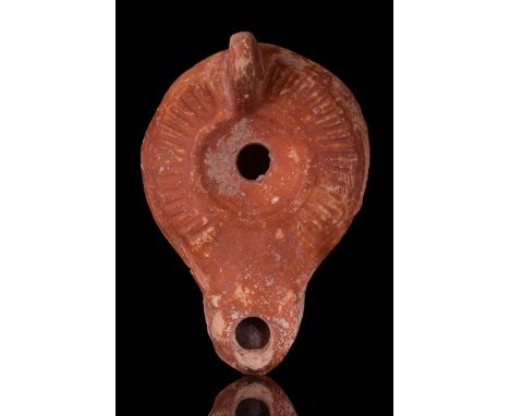 Ca. 100-300 AD A wonderfully preserved, mould-made terracotta oil lamp featuring a large, rounded concave body with a central