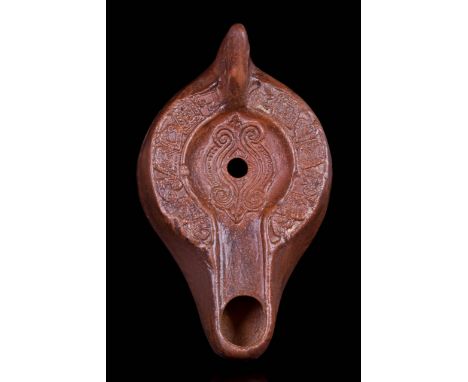 Ca. 300-500 AD A wonderfully preserved, mould-made terracotta lamp featuring a sunken discus, a central pour hole, a wide cha