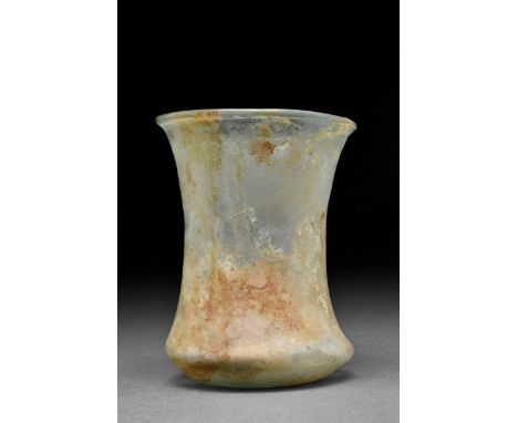 Ca. 200-300 AD A yellowish-light green glass beaker with a flaring rim, lightly piriform body, and ring foot; slight encrusta