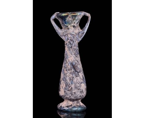 Ca. 4th-5th Century AD A glass unguentarium with a piriform body standing on an applied disc base featuring an everted mouth 