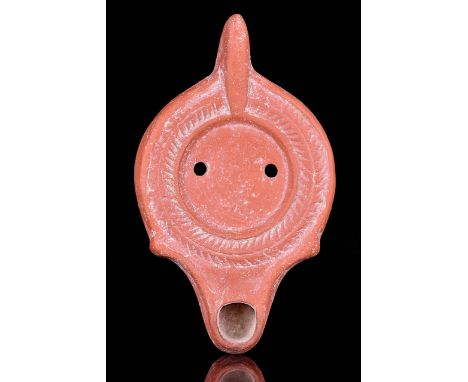 Ca. 4th-5th Century AD A beautiful terracotta oil lamp featuring a discus with a wick hole and a vent hole adorned with a lau
