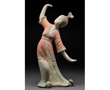 Ca. 618-906 AD A terracotta Tang Dynasty female dancer wearing a long flowing gown with her hands uncovered. The dress is a d