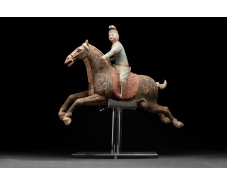 Ca. 618-906 AD A breathtakingly beautiful terracotta polo rider depicted sitting on a galloping horse. The figure's face is s