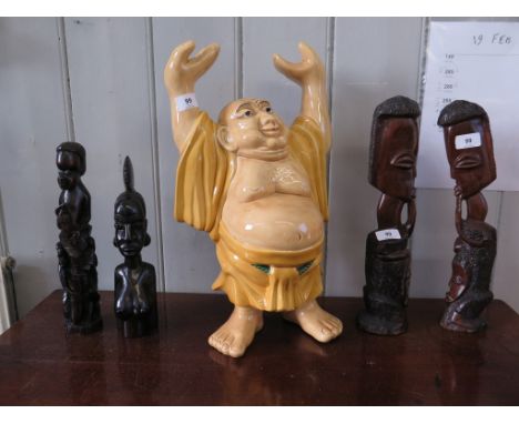 A ceramic figure of a Buddhist man, his hands aloft, 47 cm high and four African hardwood carvings (5) 