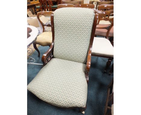 A Victorian mahogany nursing chair with pierced spindle gallery arms and raised on circular tapering front legs and ceramic c