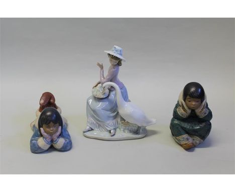 Lladro figure depicting a young lady seated on a boulder with a goose stealing grapes from her basket, two Lladro/Nao figures