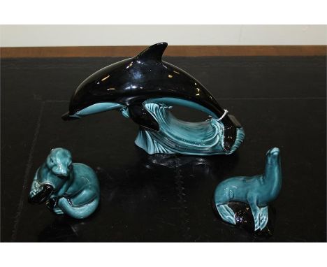 Poole pottery, to include a dolphin of large proportions, an otter with fish and a seal, (3)