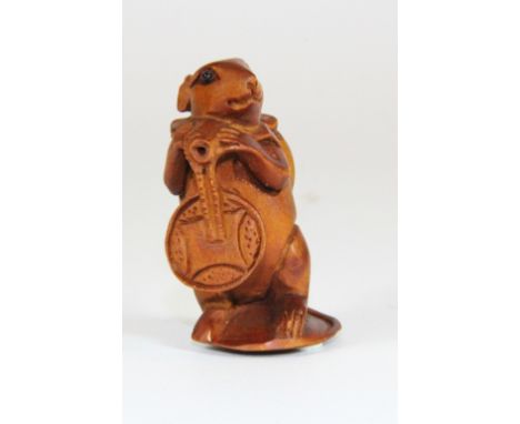 A carved fruitwood netsuke of a mouse carrying a peach and a cash