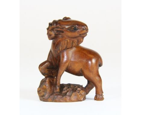 A carved fruitwood netsuke of a bearded goat with black onyx eyes