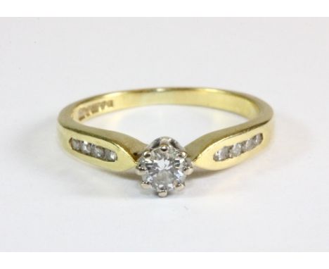 An 18ct gold diamond solitaire ring with diamond set shoulders (K)