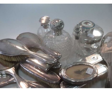 A collection of silverware including silver backed dressing table items, silver topped glass perfume bottles, silver and enam