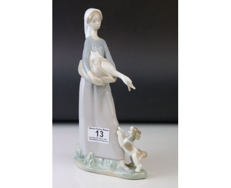 A Lladro figure of a young woman carrying a goose with a playful dog at her feet.